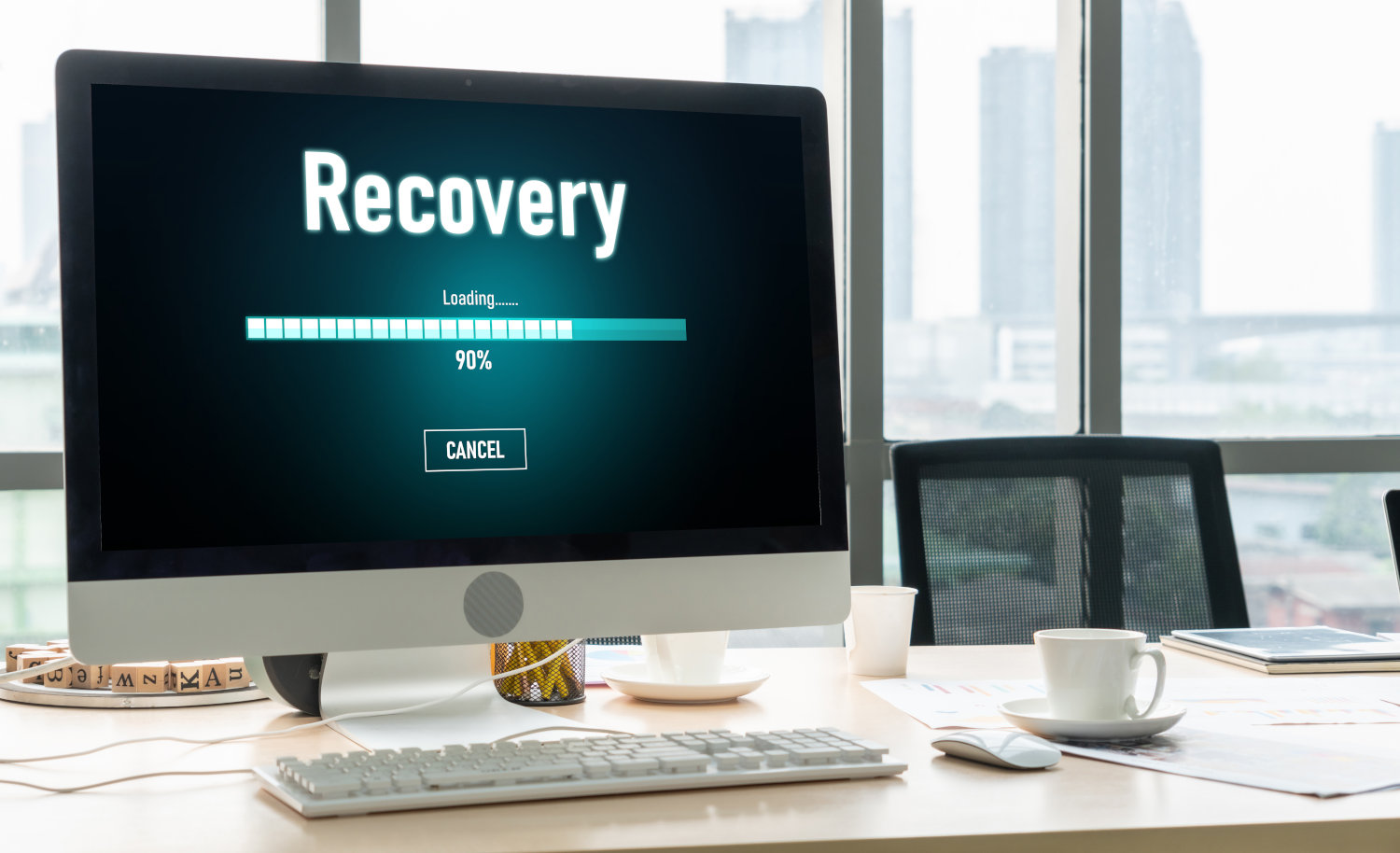 A laptop on a desk with the word Recovery on the screen and a progress bar