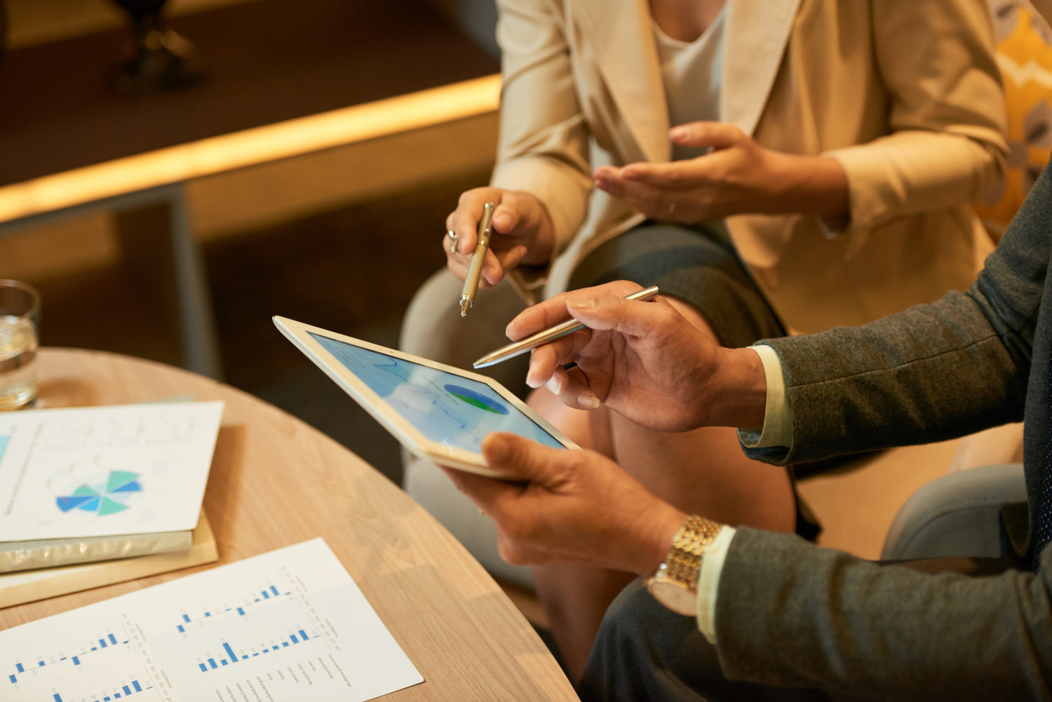 A group of people discussing a financial graph while looking at a tablet