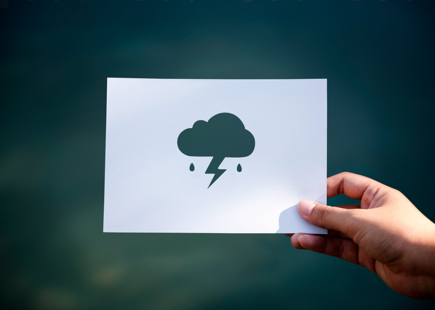 A cutout of a cloud with lightening in front of a dark background