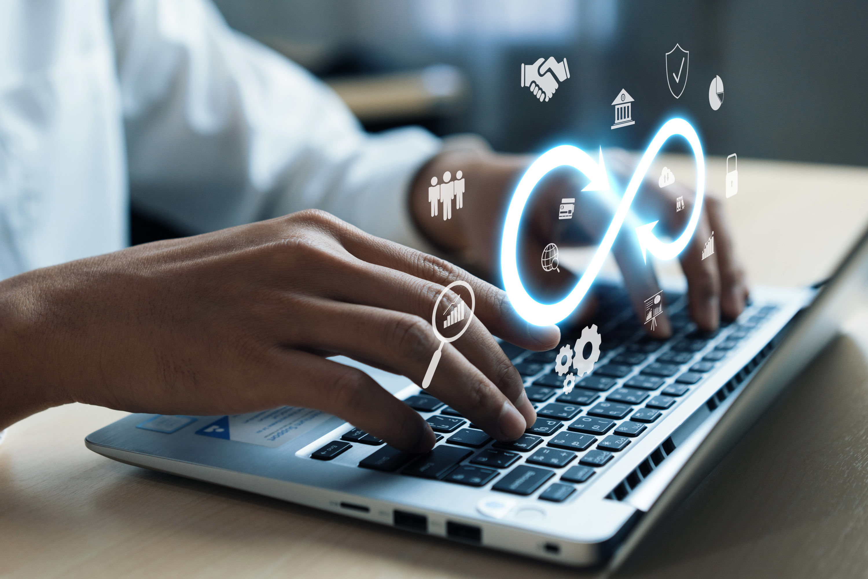 male hands typing on a laptop with devops symbols floating above the keyboard